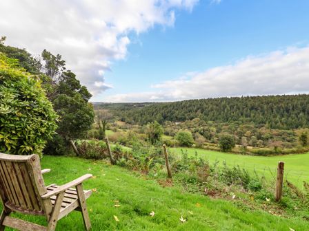 A chair on grass overlooking a valley at Thimble Lodge in Gunnislake
