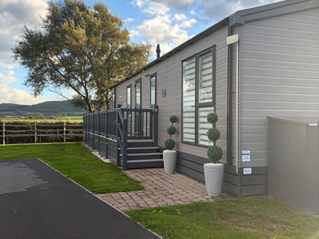 A mobile home with steps and planters at Ty Mawr Holiday Park Swift Toronto Lodge Towyn