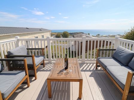 An outdoor seating area with a table and chairs overlooking the sea at Club Sahara, Sandy Bay, Exmouth