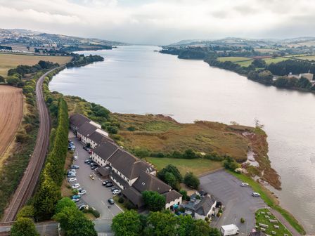 An aerial view of a river with buildings and a parking lot at Avocet in Kingsteignton