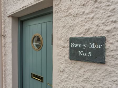 A door with a circular window and sign reading Swn-y-Mor No. 5 at Swn y Mor (Wexham) Beaumaris