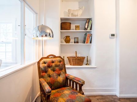 A living room with a chair and books on a shelf at a property in unspecified location
