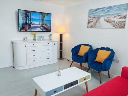 A living room with a television and blue armchairs at the property located in an unspecified area