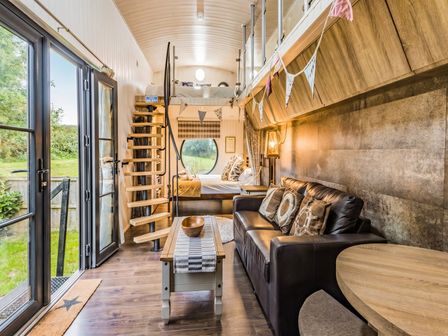 A living room with a sofa and stairs leading to a bed at the property