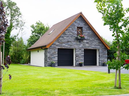 A garage with stone exterior and plants at Limavady Cherry Tree Apartment, Sleeps 2 and Parking, Limavady