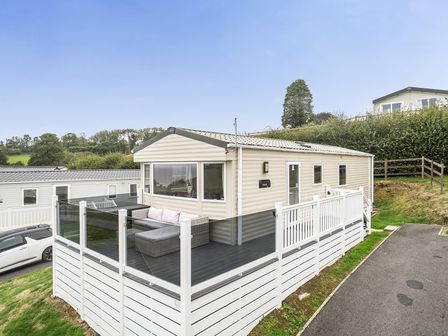 A caravan with a deck and sofa at Ty dee seaview escapes in Looe
