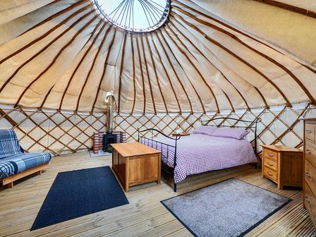 A yurt with a bed and sofa bed at Yurt, Sleeps 2 with BBQ and Fire Pit, Tregooden Farm near St Tudy
