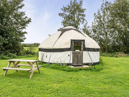 A yurt with a door and table in an outdoor area at Yurt, Sleeps 5 and Dogs Welcome