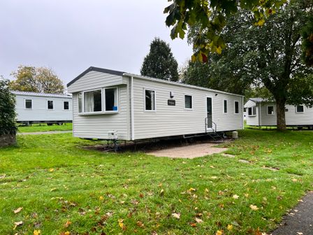 A mobile home with front steps in a grassy area at Hafan y Mor - 159 Snowdonia Pwllheli