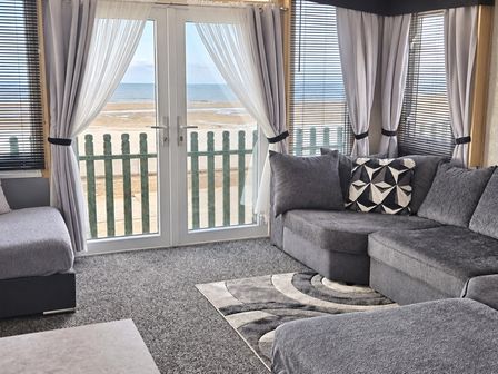 A living room with a sliding door and ocean view at 3 Bedroom Seafront Caravan, Sleeps 6 with Parking
