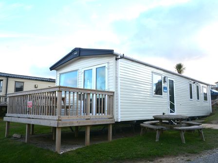A mobile home with a deck and outdoor table at Perran Sands Holiday Park - 615 Chy-an-Mor Perranporth