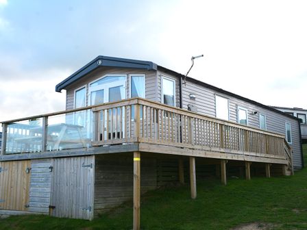 A mobile home with a deck and stairs at Perran Sands Holiday Park - 620 Chy An Mor, Perranporth