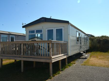 A static caravan with a wooden deck at Perran Sands Holiday Park - 725 Kernow View in Perranporth