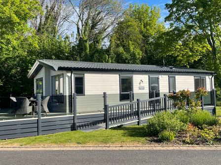A cabin with a deck and outdoor seating at Hoburne Devon Bay - Woodland Glade 24 in Paignton