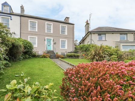 A front garden with a pathway leading to a house with a turquoise door at Garth Craig in Porthmadog