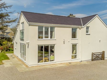 A two story beige house with large windows and a gravel driveway at Bron Gors in Edern near Morfa Nefyn