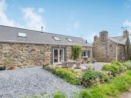 Stone cottages with slate roofs and outdoor seating area with table and chairs at Trefaes Newydd in Sarn Meyllteyrn near Abersoch