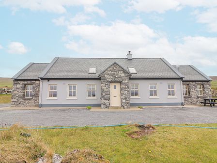 A single-story house with stone and gray walls and a gravel driveway at Cunna Ban in Fanore County Clare