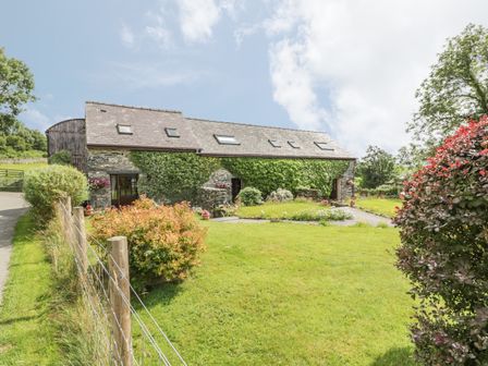 Stone house with ivy on the walls and a garden with bushes and grass at Arfron Penrhyddion Pella in Capel Garmon near Betws-y-Coed