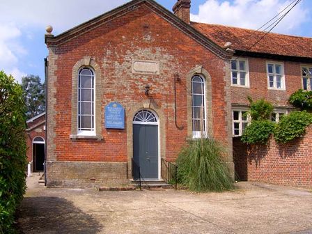 A brick building with a central grey door and tall narrow windows at The Methodist Chapel in Whiteparish near Salisbury