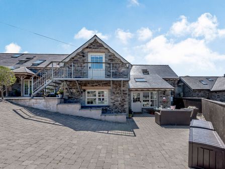 A stone house with exterior stairs and outdoor seating area at Ysgubor Isaf in Brongest near Newcastle Emlyn