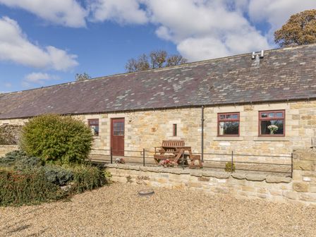 A stone cottage with a slate roof wooden door windows and outdoor seating at Ridge Cottage in Whitridge