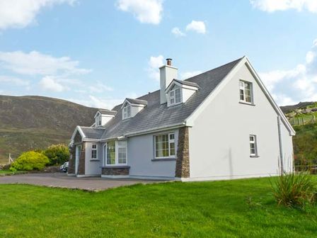 A white house with gray roof and dormer windows on a green lawn at Carraig Oisin Baleen near Waterville County Kerry