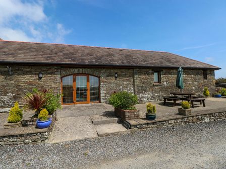 An outdoor area with stone building and furniture at The Stall in Penuel near Llanmorlais