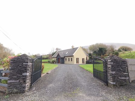 A house with a gravel driveway and metal gates at Rocklands House in Beaufort County Kerry
