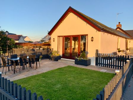 A small fenced yard with patio furniture lawn and potted plants outside a house at Potters Barn in Begelly near Kilgetty
