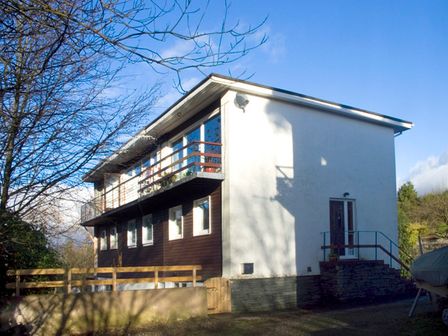 A two-story house with a balcony and a wooden fence surrounded by trees at Park View in Bowness-on-Windermere