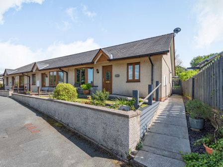 A row of single story houses with gardens and a paved sidewalk at Gorwel in Llan Ffestiniog near Blaenau Ffestiniog