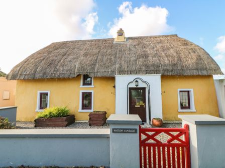A thatched roof cottage with yellow walls and a red gate at Sutton Cottage Ballysheen near Rosslare Harbour County Wexford