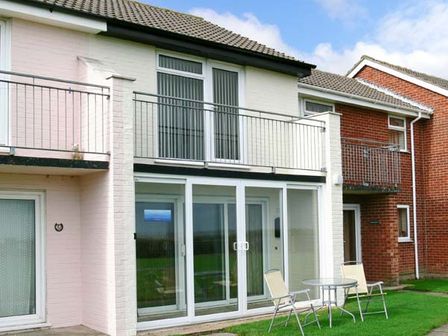 A two story house exterior with balconies and patio furniture on grass at Seascope in Kessingland near Lowestoft
