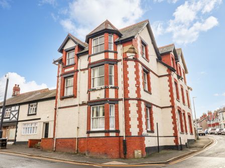 An exterior view of a multi-story residential building with red brick and white walls on a street corner at Ship Inn in Old Colwyn