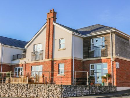 A two-story residential building with brick and siding exterior and balconies at Beach View in Benllech near Red Wharf Bay