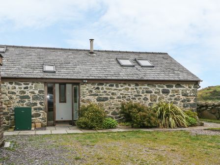 A stone cottage with three skylights on the roof and plants in front at Y Beudy in Criccieth
