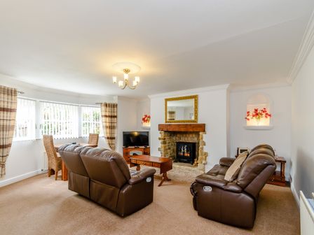 A living room with leather sofas a wooden coffee table a fireplace and a dining table near windows at The Bolthole in Whitby