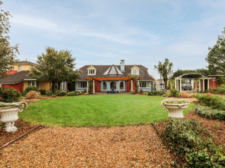 A house with a circular lawn and gravel path surrounded by plants and trees at Ballysheen House in Ballysheen near Rosslare Harbour County Wexford
