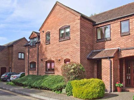 A brick residential building with windows bushes and parked cars at 9 Bancroft Place in Stratford-upon-Avon