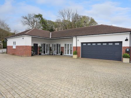A driveway in front of a single story house with a two car garage and patio furniture at Oakwood Stables in Conwy