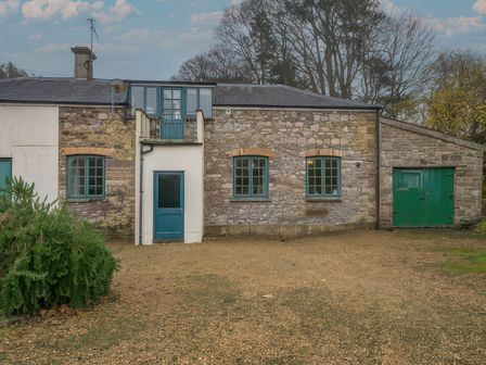 The exterior of a stone house with blue-framed windows and doors and a green garage door at The Coach House in Gilwern near Crickhowell and Abergavenny