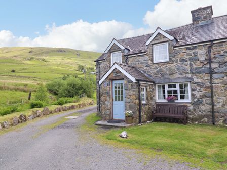 A cottage with a blue door and bench at Stabal Cottage in Dolgellau