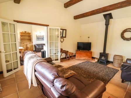 A living room with brown leather sofas a wood burning stove and a TV at Parlour Barn in Pershore