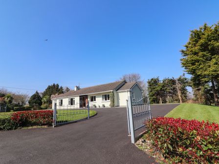 A single-story house with a driveway and iron gates surrounded by trees and shrubs at Gap of Dunloe Beaufort near Killorglin County Kerry
