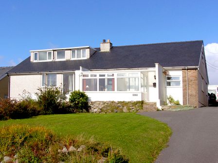 A single-story house with a dark roof a driveway and a lawn at Trem y Mor in Llanfair near Harlech