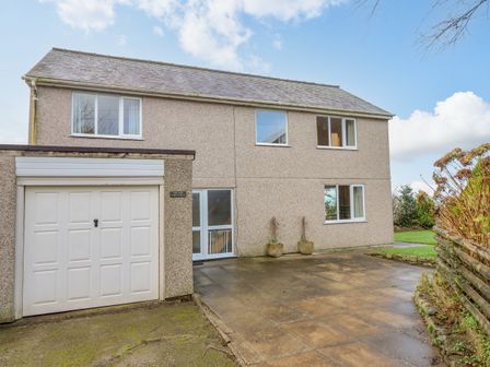 A two-story house with a garage and paved driveway at The Villa in Harlech
