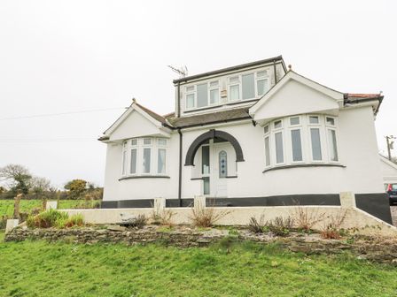 A white house with two bay windows and a black arched entrance at Trelydarth Penhallow near Perranporth