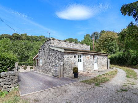 A stone building with a driveway and a plant pot at The Lambing Shed in Dyserth near Prestatyn