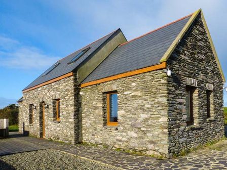 A stone house with multiple windows and skylights under a blue sky at Corr an Droma in Schull County Cork